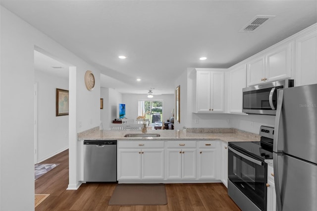 69 Pin Oak Dr, Palm Coast, FL 32164 - kitchen with stainless steel appliances, dark wood-type flooring, recessed lighting, white cabinets, and light stone counters