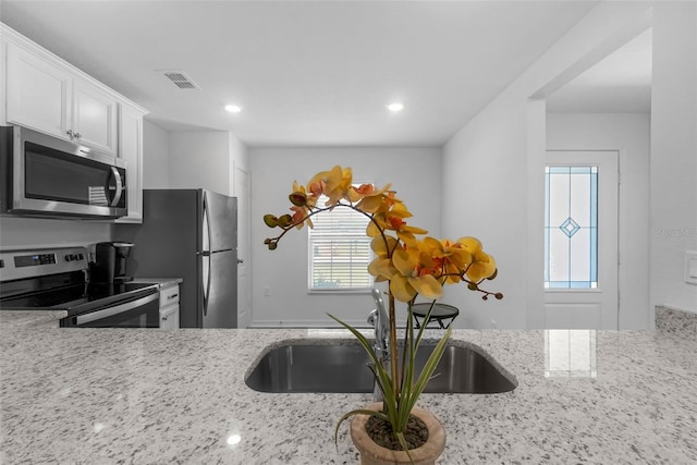 69 Pin Oak Dr, Palm Coast, FL 32164 - kitchen with stainless steel appliances, plenty of natural light, light stone countertops, white cabinets, and recessed lighting