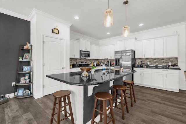 1608 Mohegan Blvd, Kissimmee, FL 34744 - kitchen with stainless steel appliances, ornamental molding, dark wood-style floors, white cabinetry, and tasteful backsplash