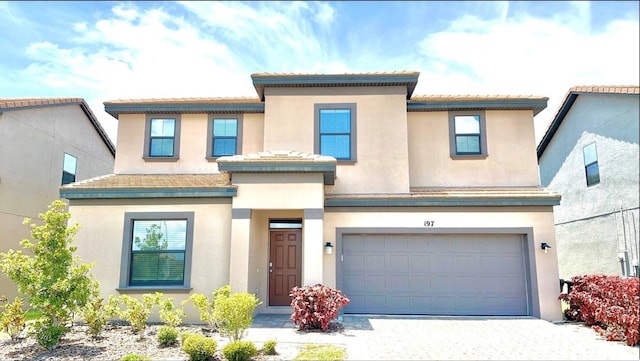 197 Macaulays Cv, Haines City, FL 33844 - view of front of property featuring an attached garage, decorative driveway, stucco siding, and a tiled roof