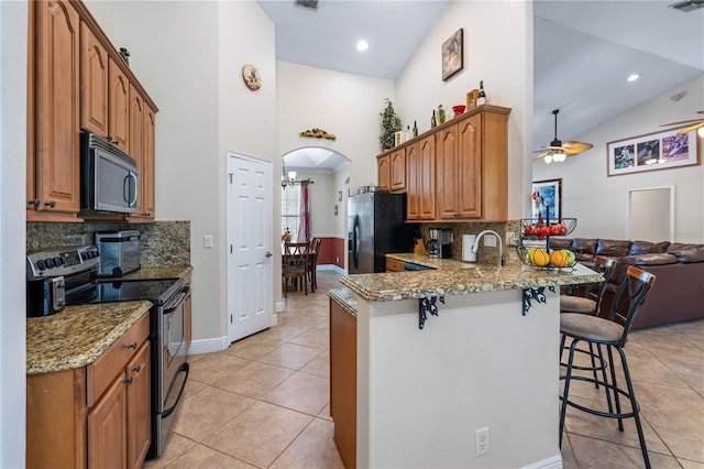 859 Leather Fern Ln, Mims, FL 32754 - kitchen with appliances with stainless steel finishes, ceiling fan, a breakfast bar area, a peninsula, and light tile patterned flooring
