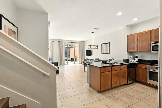 2617 Bugatti Ct, Kissimmee, FL 34746 - kitchen featuring appliances with stainless steel finishes, a peninsula, light tile patterned floors, dark countertops, and brown cabinets