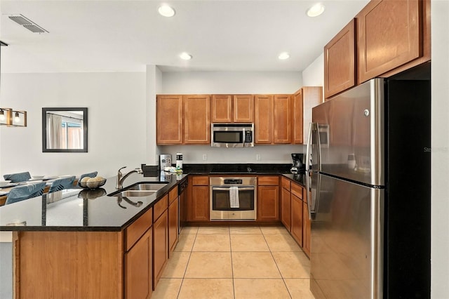 2617 Bugatti Ct, Kissimmee, FL 34746 - kitchen featuring black appliances, a peninsula, brown cabinetry, light tile patterned floors, and recessed lighting