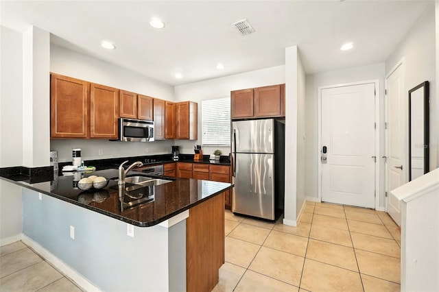 2617 Bugatti Ct, Kissimmee, FL 34746 - kitchen with stainless steel appliances, a peninsula, light tile patterned floors, brown cabinetry, and recessed lighting