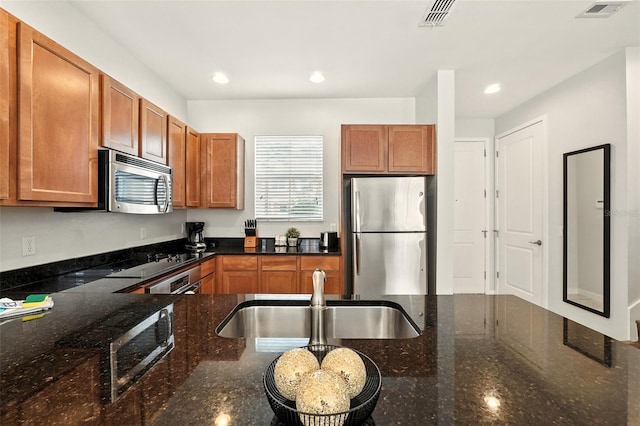 2617 Bugatti Ct, Kissimmee, FL 34746 - kitchen featuring appliances with stainless steel finishes, recessed lighting, brown cabinetry, and dark stone counters