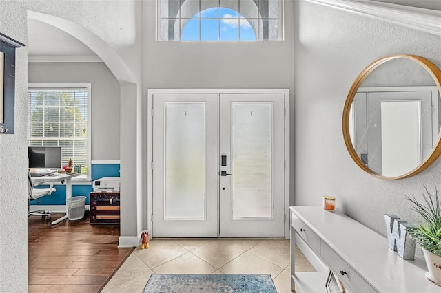 4323 Kezar Ct, Belle Isle, FL 32812 - entrance foyer with french doors, crown molding, a textured wall, tile patterned floors, and arched walkways