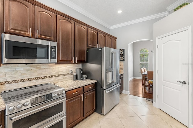 4323 Kezar Ct, Belle Isle, FL 32812 - kitchen featuring stainless steel appliances, arched walkways, decorative backsplash, light tile patterned flooring, and ornamental molding