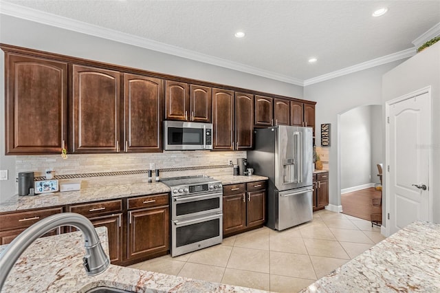 4323 Kezar Ct, Belle Isle, FL 32812 - kitchen featuring stainless steel appliances, decorative backsplash, dark brown cabinets, light tile patterned flooring, and light stone counters
