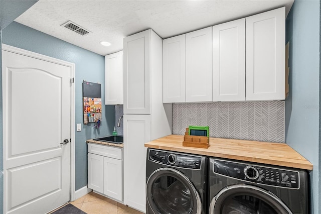 4323 Kezar Ct, Belle Isle, FL 32812 - washroom featuring washer and dryer, cabinet space, a textured ceiling, and light tile patterned floors