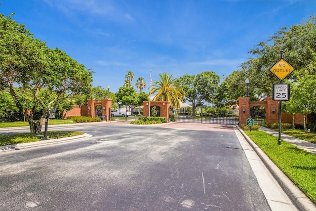 4323 Kezar Ct, Belle Isle, FL 32812 - view of asphalt street with traffic signs, a gate, curbs, a gated entry, and sidewalks