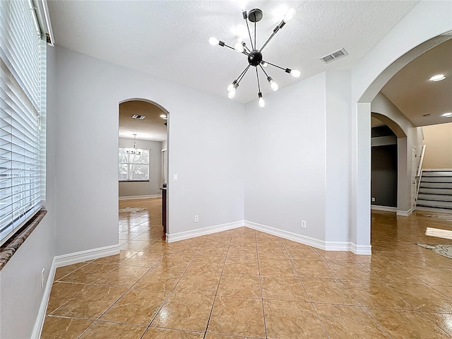 229 Largovista Dr, Oakland, FL 34787 - unfurnished room with a chandelier, tile patterned flooring, arched walkways, and a textured ceiling