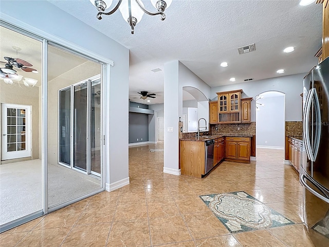 229 Largovista Dr, Oakland, FL 34787 - kitchen featuring brown cabinets, arched walkways, freestanding refrigerator, dishwashing machine, and backsplash