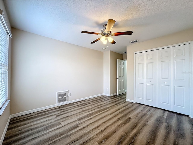 229 Largovista Dr, Oakland, FL 34787 - unfurnished bedroom with wood finished floors, multiple windows, a closet, a textured ceiling, and ceiling fan