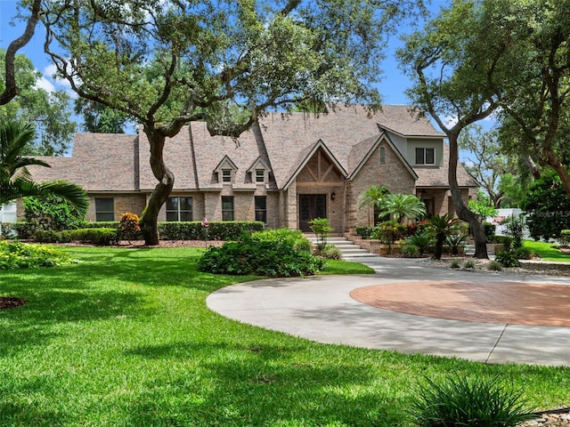 9045 Mossy Oak Ln, Clermont, FL 34711 - tudor home with a front lawn, brick siding, and curved driveway