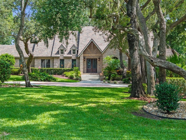 9045 Mossy Oak Ln, Clermont, FL 34711 - english style home featuring french doors, a front yard, and brick siding