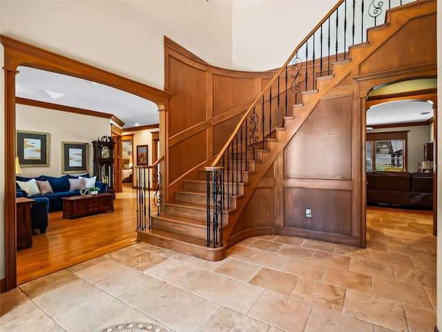 9045 Mossy Oak Ln, Clermont, FL 34711 - stairs featuring stone tile flooring, ornamental molding, arched walkways, and a high ceiling
