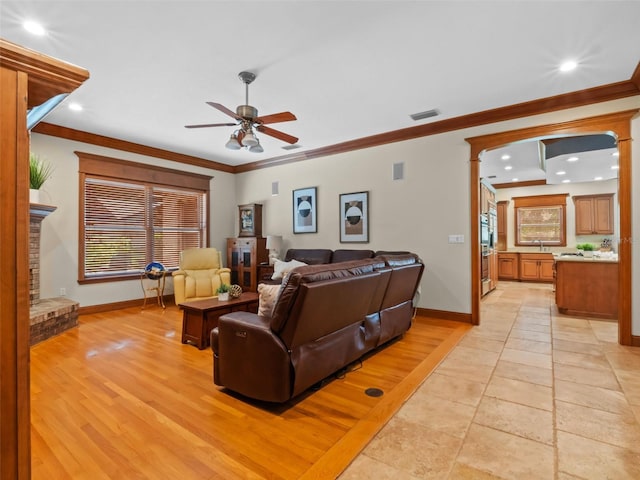 9045 Mossy Oak Ln, Clermont, FL 34711 - living room with ceiling fan, recessed lighting, ornamental molding, a fireplace with raised hearth, and light wood-type flooring