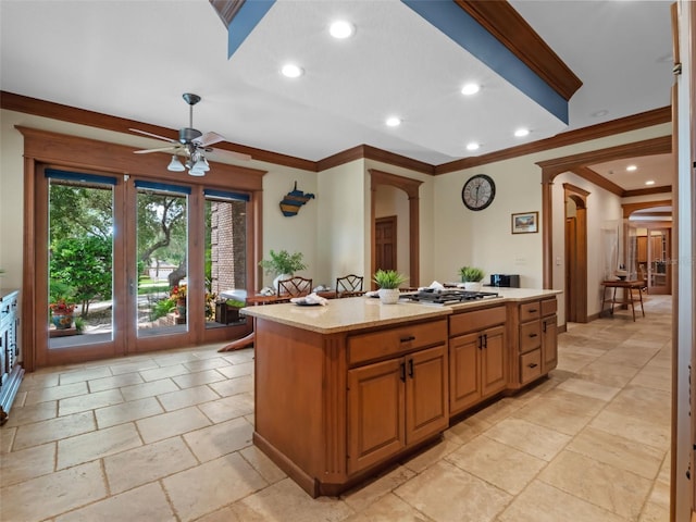 9045 Mossy Oak Ln, Clermont, FL 34711 - kitchen with stainless steel gas stovetop, ceiling fan, arched walkways, a kitchen island, and crown molding
