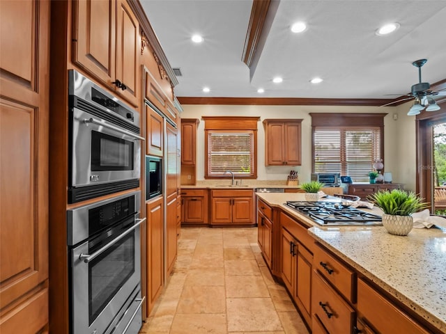 9045 Mossy Oak Ln, Clermont, FL 34711 - kitchen featuring stainless steel appliances, brown cabinetry, light stone countertops, ornamental molding, and a ceiling fan