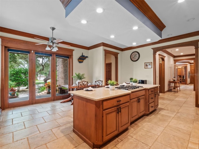 9045 Mossy Oak Ln, Clermont, FL 34711 - kitchen featuring arched walkways, crown molding, a ceiling fan, a center island, and stainless steel gas cooktop