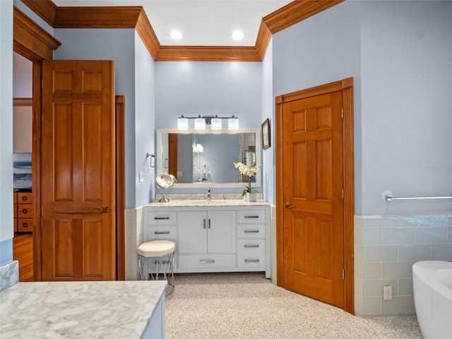 9045 Mossy Oak Ln, Clermont, FL 34711 - bathroom with tile walls, vanity, ornamental molding, a freestanding tub, and a wainscoted wall