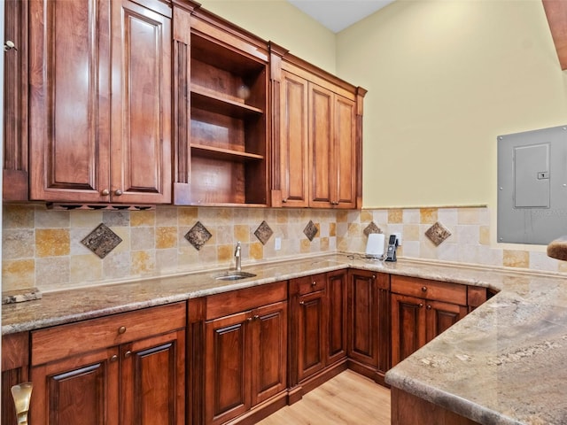 9045 Mossy Oak Ln, Clermont, FL 34711 - kitchen featuring electric panel, open shelves, decorative backsplash, light stone counters, and light wood finished floors