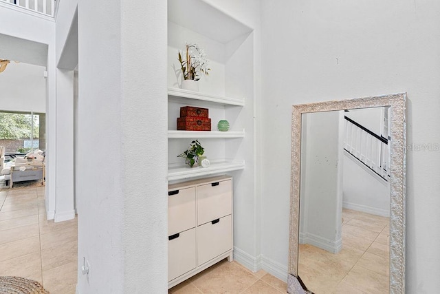 14897 Ellingsworth Ln, Winter Garden, FL 34787 - hallway featuring light tile patterned flooring, built in shelves, and stairs