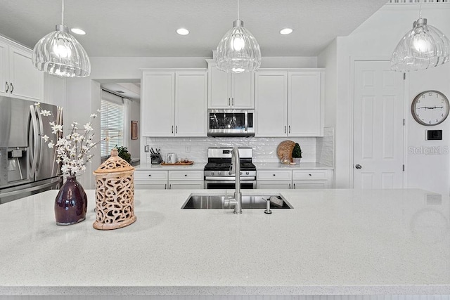 14897 Ellingsworth Ln, Winter Garden, FL 34787 - kitchen featuring appliances with stainless steel finishes, white cabinetry, backsplash, light stone counters, and recessed lighting