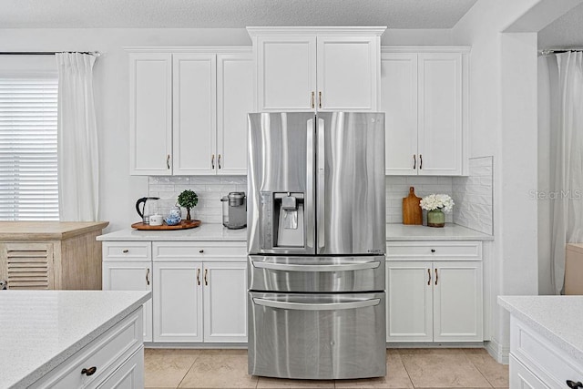 14897 Ellingsworth Ln, Winter Garden, FL 34787 - kitchen featuring stainless steel fridge, white cabinetry, tasteful backsplash, and light tile patterned floors
