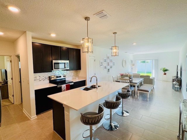 439 Cool Summer Ln, Davenport, FL 33837 - kitchen featuring appliances with stainless steel finishes, tasteful backsplash, a breakfast bar, light countertops, and pendant lighting