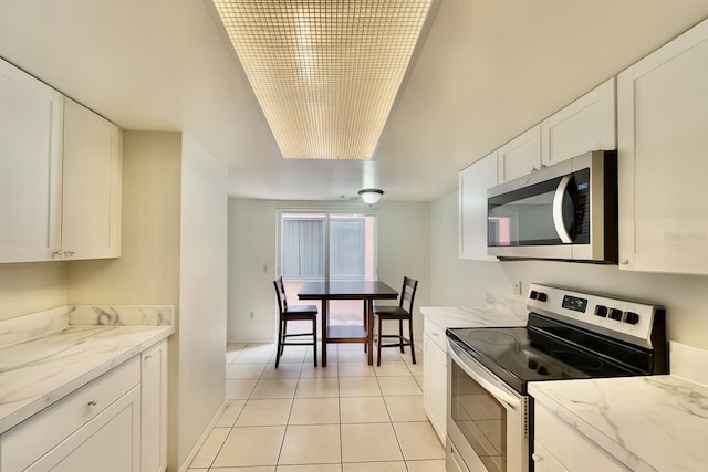 2242 Atrium Cir, Orlando, FL 32808 - kitchen with appliances with stainless steel finishes, light tile patterned floors, white cabinetry, and light stone counters