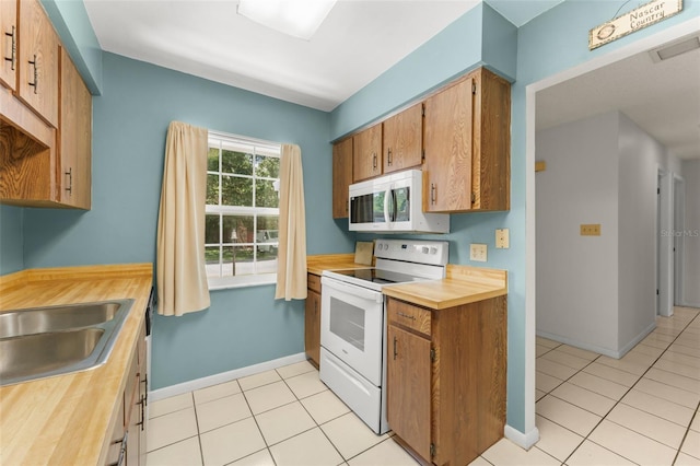 17 Rosewood Dr, Davenport, FL 33837 - kitchen featuring white appliances, butcher block counters, light tile patterned floors, and brown cabinetry