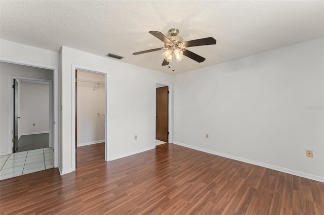 17 Rosewood Dr, Davenport, FL 33837 - unfurnished bedroom featuring wood finished floors, a walk in closet, a textured ceiling, and ceiling fan
