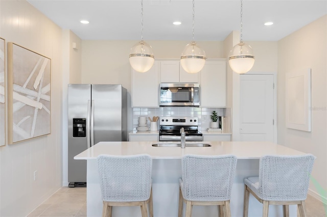 2304 Southbury Dr, Kissimmee, FL 34744 - kitchen featuring stainless steel appliances, a center island with sink, decorative backsplash, light countertops, and a kitchen bar