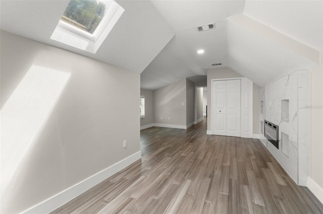 109 E 12th Ave, Windermere, FL 34786 - unfurnished living room featuring a skylight, vaulted ceiling, wood finished floors, and a premium fireplace