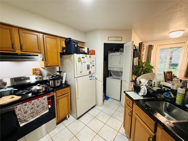 4690 Sussex Ter Unit 103, Orlando, FL 32811 - kitchen featuring stainless steel range with electric cooktop, under cabinet range hood, estacked washer and dryer, freestanding refrigerator, and brown cabinets