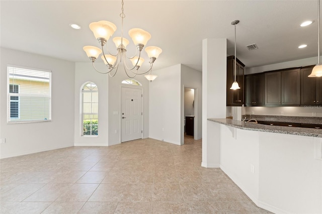 1218 Vienna Square Dr, Winter Haven, FL 33884 - kitchen featuring dark brown cabinetry, dark stone counters, a chandelier, hanging light fixtures, and recessed lighting