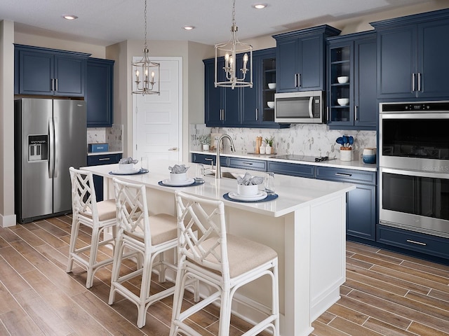 1229 Pampus Dr, Daytona Beach, FL 32124 - kitchen featuring stainless steel appliances, blue cabinets, wood finished floors, a chandelier, and recessed lighting