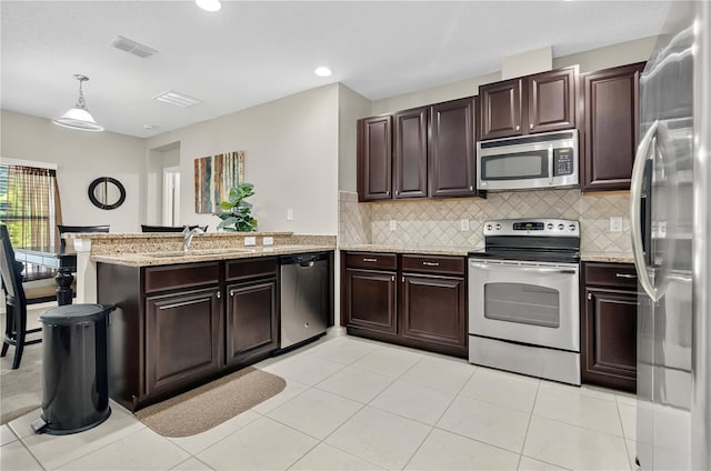1414 Marsh Meadow Ln, Davenport, FL 33896 - kitchen with appliances with stainless steel finishes, a peninsula, backsplash, pendant lighting, and dark brown cabinetry