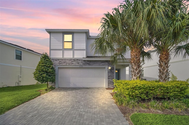 8940 Zurich Ln, Kissimmee, FL 34747 - view of front of home with an attached garage, decorative driveway, stone siding, and a yard
