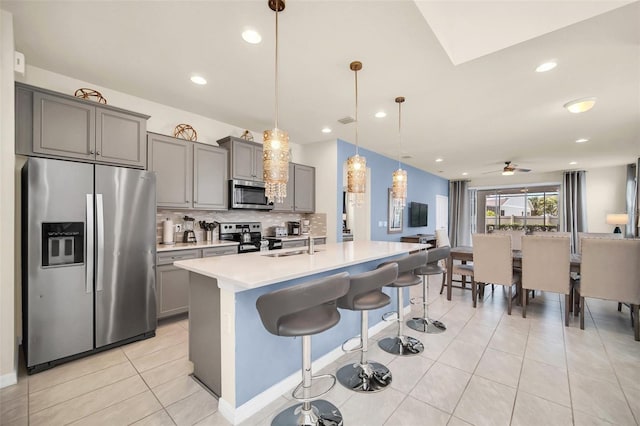 8940 Zurich Ln, Kissimmee, FL 34747 - kitchen with appliances with stainless steel finishes, gray cabinets, tasteful backsplash, light countertops, and a kitchen breakfast bar