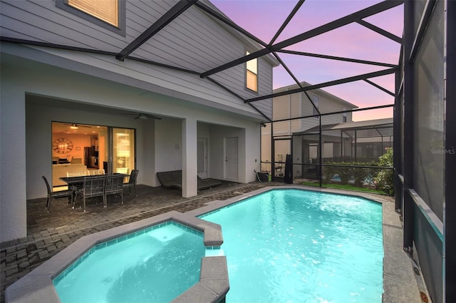 8940 Zurich Ln, Kissimmee, FL 34747 - pool at dusk with a patio, a pool with connected hot tub, a lanai, and a ceiling fan