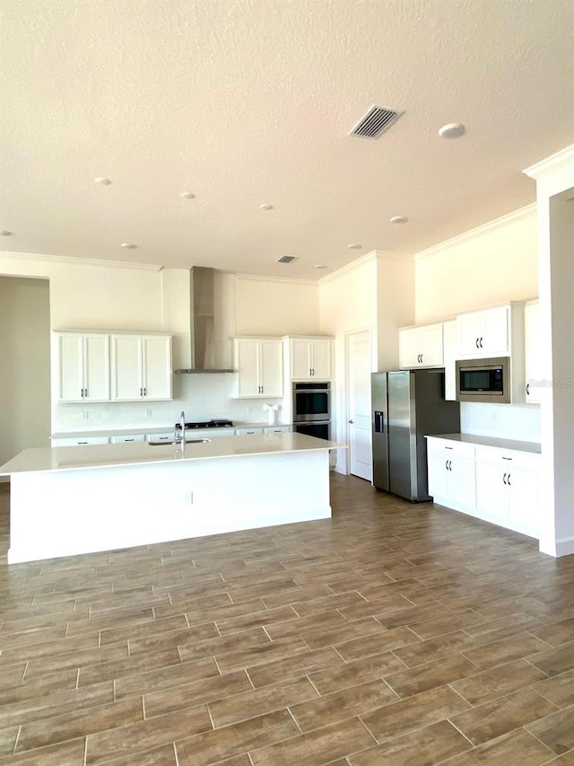 16071 Barkly Ridge Ct, Winter Garden, FL 34787 - kitchen with wall chimney exhaust hood, appliances with stainless steel finishes, ornamental molding, a textured ceiling, and a large island with sink