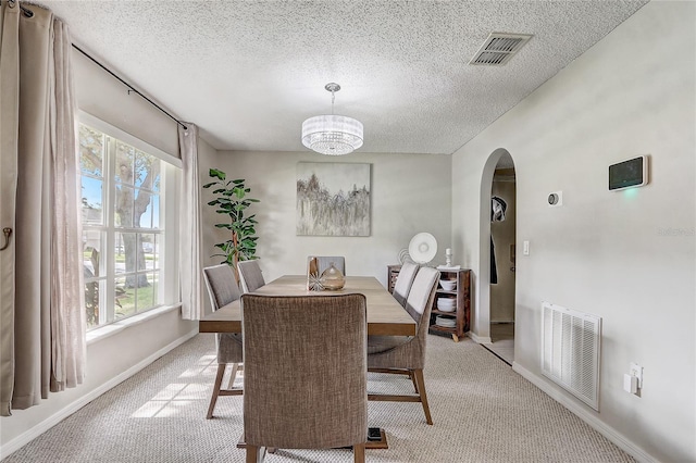 569 Yearling Cove Loop, Apopka, FL 32703 - dining space with arched walkways, a textured ceiling, healthy amount of natural light, and light colored carpet