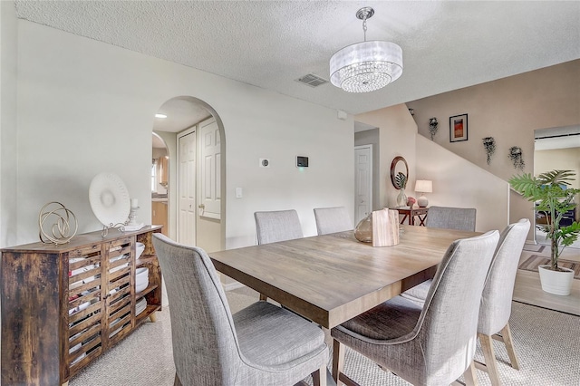 569 Yearling Cove Loop, Apopka, FL 32703 - dining area featuring light colored carpet, a chandelier, arched walkways, and a textured ceiling