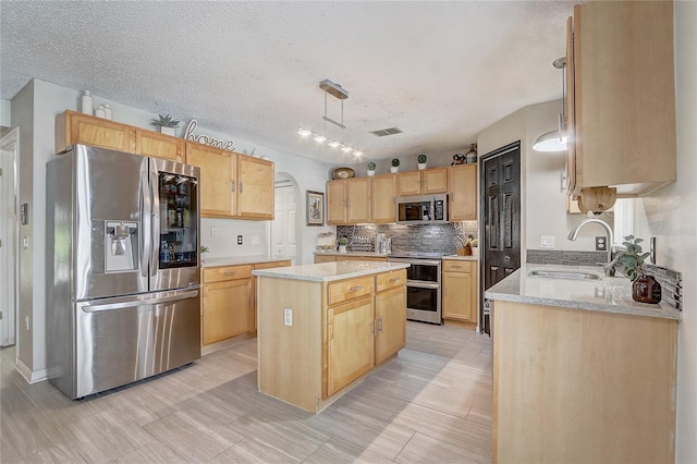 569 Yearling Cove Loop, Apopka, FL 32703 - kitchen with stainless steel appliances, a kitchen island, light brown cabinetry, tasteful backsplash, and a textured ceiling
