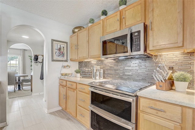 569 Yearling Cove Loop, Apopka, FL 32703 - kitchen featuring stainless steel appliances, light brown cabinets, arched walkways, and decorative backsplash