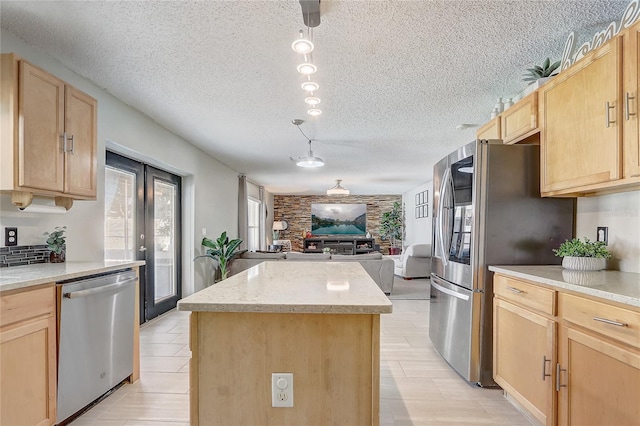 569 Yearling Cove Loop, Apopka, FL 32703 - kitchen featuring appliances with stainless steel finishes, light brown cabinets, a kitchen island, open floor plan, and a textured ceiling