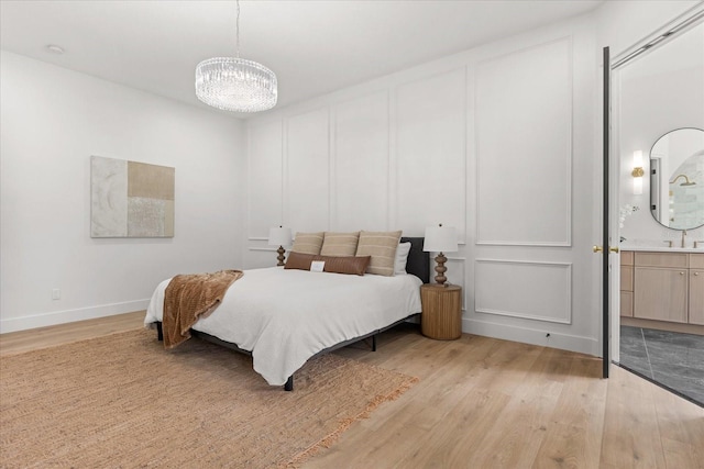 619 Largovista Dr, Oakland, FL 34787 - bedroom featuring light wood finished floors, a chandelier, a decorative wall, and ensuite bathroom
