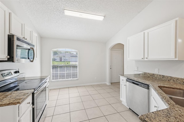 1082 Worthington Dr, Deltona, FL 32738 - kitchen featuring stainless steel appliances, a textured ceiling, white cabinetry, arched walkways, and light stone countertops